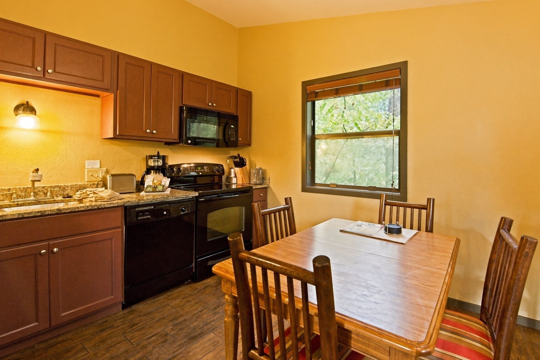 A kitchen with wooden cabinets, a microwave, a stove, and a dining table with chairs.
