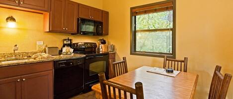 A kitchen with wooden cabinets, a microwave, a stove, and a dining table with chairs.