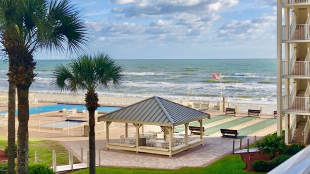 A beach view with a gazebo, pool, and a building with balconies. - Ground floor newly remodeled large condo on car free section-New Smyrna Beach  (New Smyrna Beach)