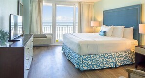 Habitación de hotel con una cama grande, televisión, escritorio y vista al océano.