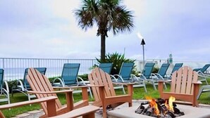 Un área de descanso junto a la playa con sillas Adirondack y una fogata.