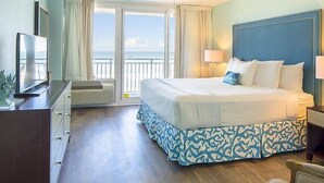 Habitación de hotel con una cama grande, televisión, escritorio y vista al océano.