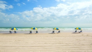 Una playa con cuatro sombrillas y sillas de playa.