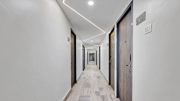 A long, narrow hallway with a tiled floor and white walls. There are doors on both sides, and the number 219 is visible on the wall. - The K11 Hotels (Chennai)