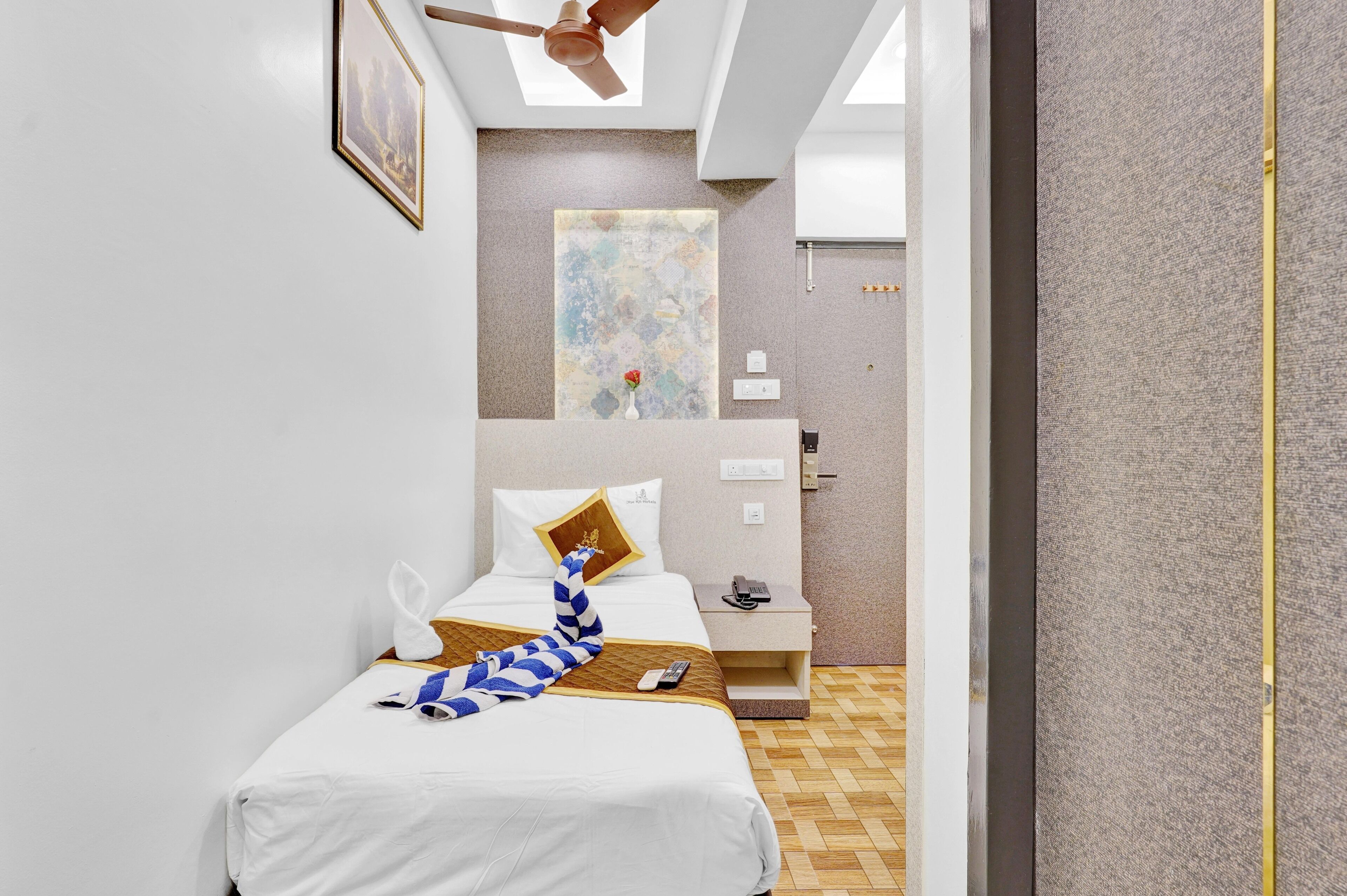A hotel room with a bed, a nightstand, a telephone, and a painting on the wall.