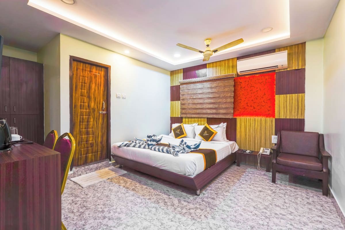 A bedroom with a bed, a desk, a chair, a wardrobe, and a ceiling fan.