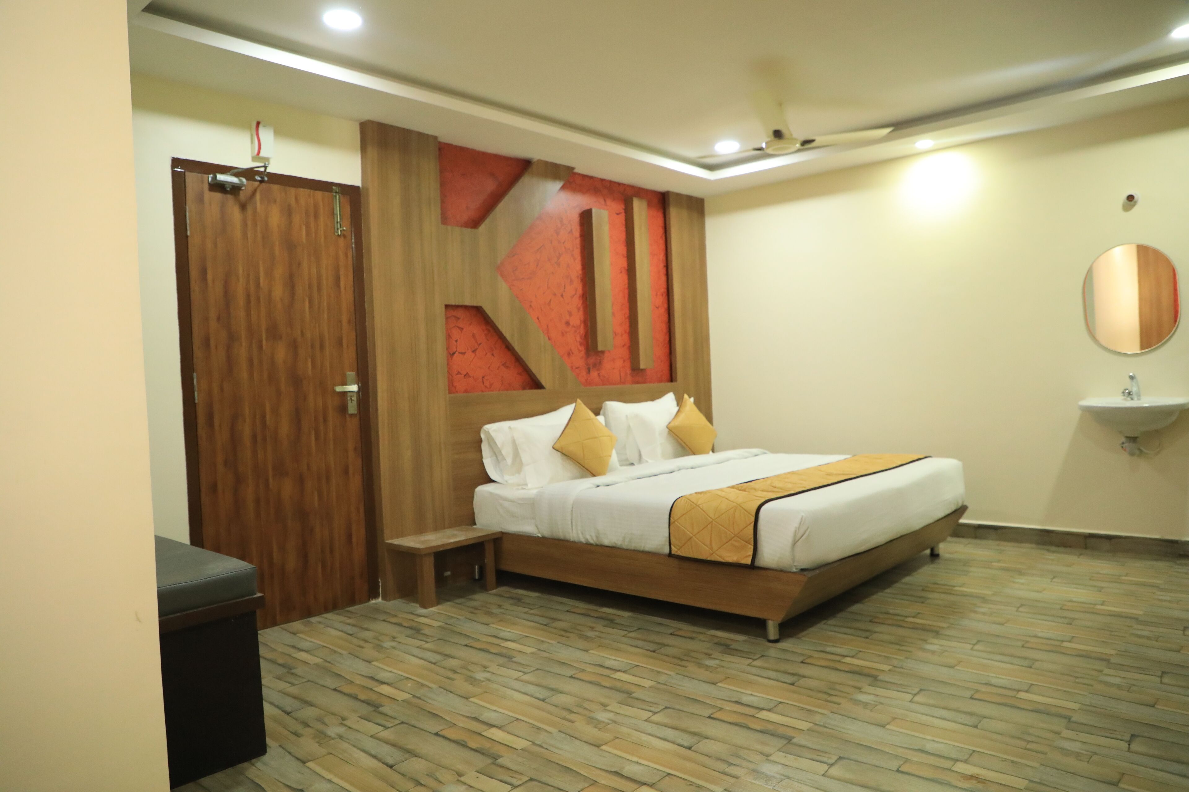 A bedroom with a wooden bed, a bedside table, a wardrobe, and a wall-mounted mirror.