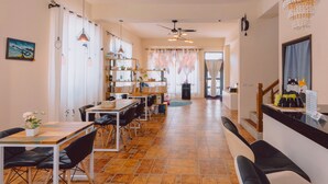 A spacious dining area with a long table and chairs, a kitchen area with a counter and shelves, and a staircase leading to another level. - Hello Inn - Hostel (Magong)