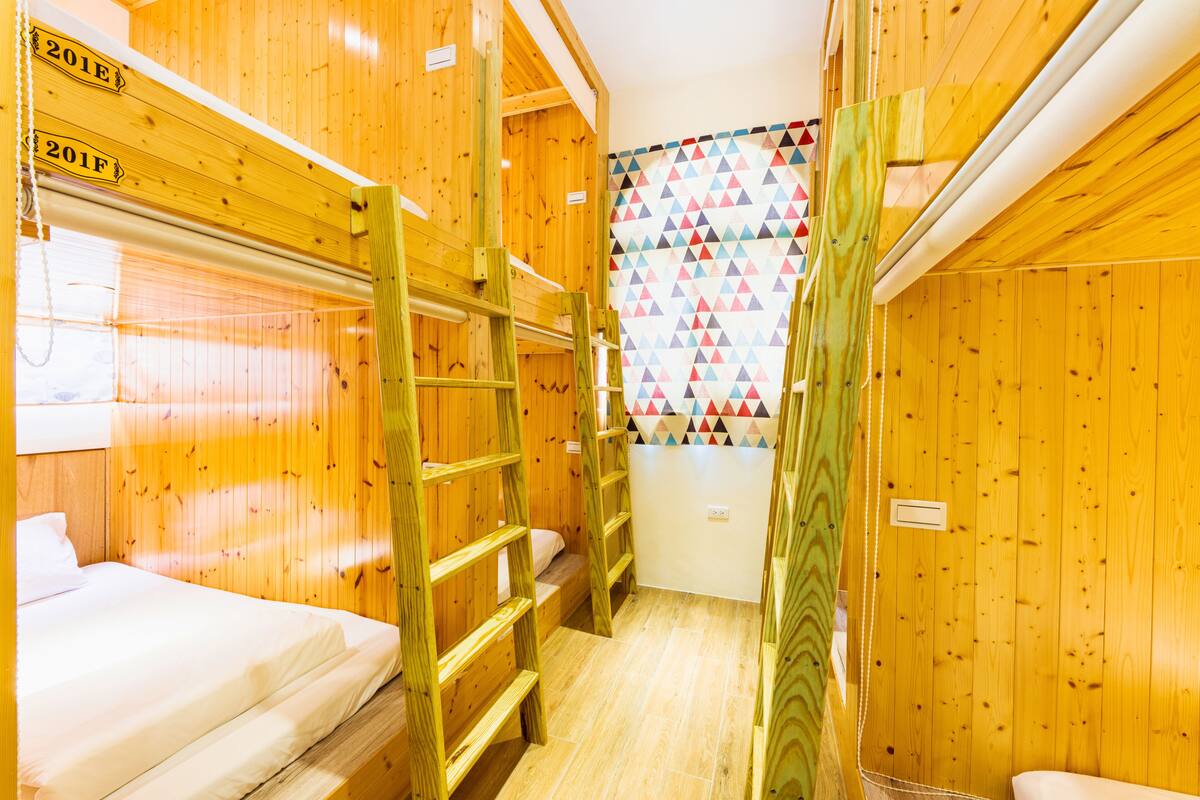 A cabin with bunk beds, wooden walls, and a colorful geometric wall hanging.