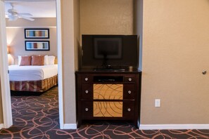 A hotel room with a bed, a television on a wooden cabinet, and a carpet with a circular pattern.