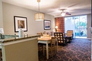 A hotel room with a dining area, a ceiling fan, and a view of the outdoors. - Orlando | Family Theme Park Retreat | Pool + Hot Tub | 2BR (Orlando)