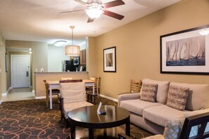 Une chambre d’hôtel comprenant un coin repas, un canapé, une table basse et un ventilateur de plafond.