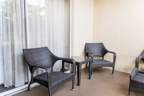 A balcony with wicker furniture, including two chairs and a table.
