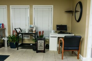 A room with a desk, computer, chair, and a wet floor sign.