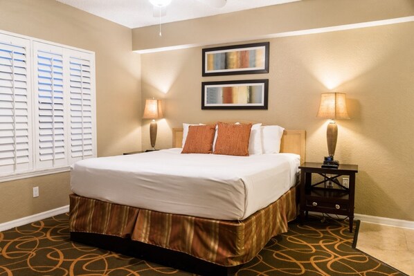 Une chambre d’hôtel avec un grand lit, deux lampes de chevet, une tête de lit et un sol recouvert de moquette.