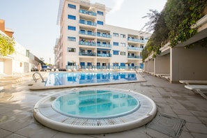 A hotel with a pool area, including a hot tub and a rectangular pool.