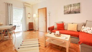 Ein Wohnzimmer mit Sofa, Couchtisch, Esstisch mit Stühlen und einem Bild an der Wand.