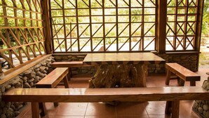 A wooden table with benches in a covered outdoor area with stone walls and a lattice window. - I am a local guide,so i can provide the  information tour in my province for you (Ha Giang city)