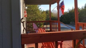 Eine Holzterrasse mit roten Geländern, einer Flagge und einem Stuhl.