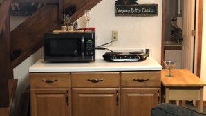 Eine Küche mit Mikrowelle, Kaffeemaschine und einem Schild mit der Aufschrift 'Welcome to the Cabin'.