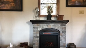 Ein Kamin mit Steinfassung, ein Fenster darüber und zwei gerahmte Bilder an der Wand.