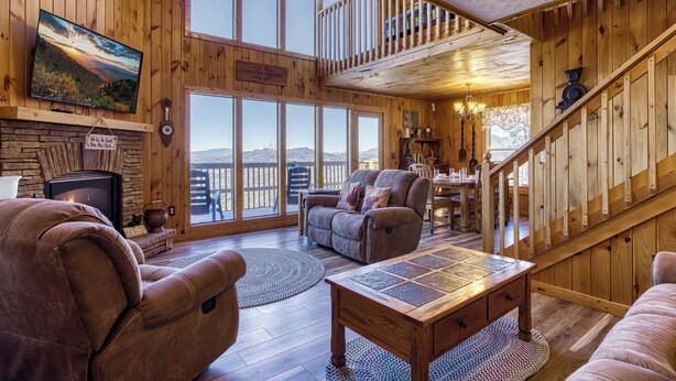 Un salon spacieux doté d’une cheminée, de sièges confortables, d’un grand téléviseur et offrant une vue sur les montagnes grâce à de grandes fenêtres.