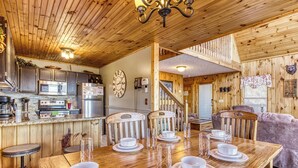 L’intérieur d’une cabane en bois comprend une cuisine, un coin repas et un escalier.