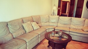Un soggiorno con un divano angolare beige, un tavolino in vetro e due vasi decorativi.