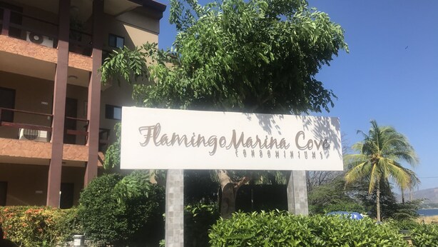 Segnaletica per Flamingo Marina Cove con vista sulla vegetazione circostante e un edificio sullo sfondo.