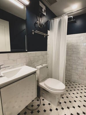 A bathroom with a white sink, toilet, and shower curtain. - House 116 (Bangkok)