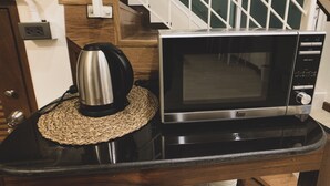 A kitchen counter with a microwave and a coffee maker. - House 116 (Bangkok)