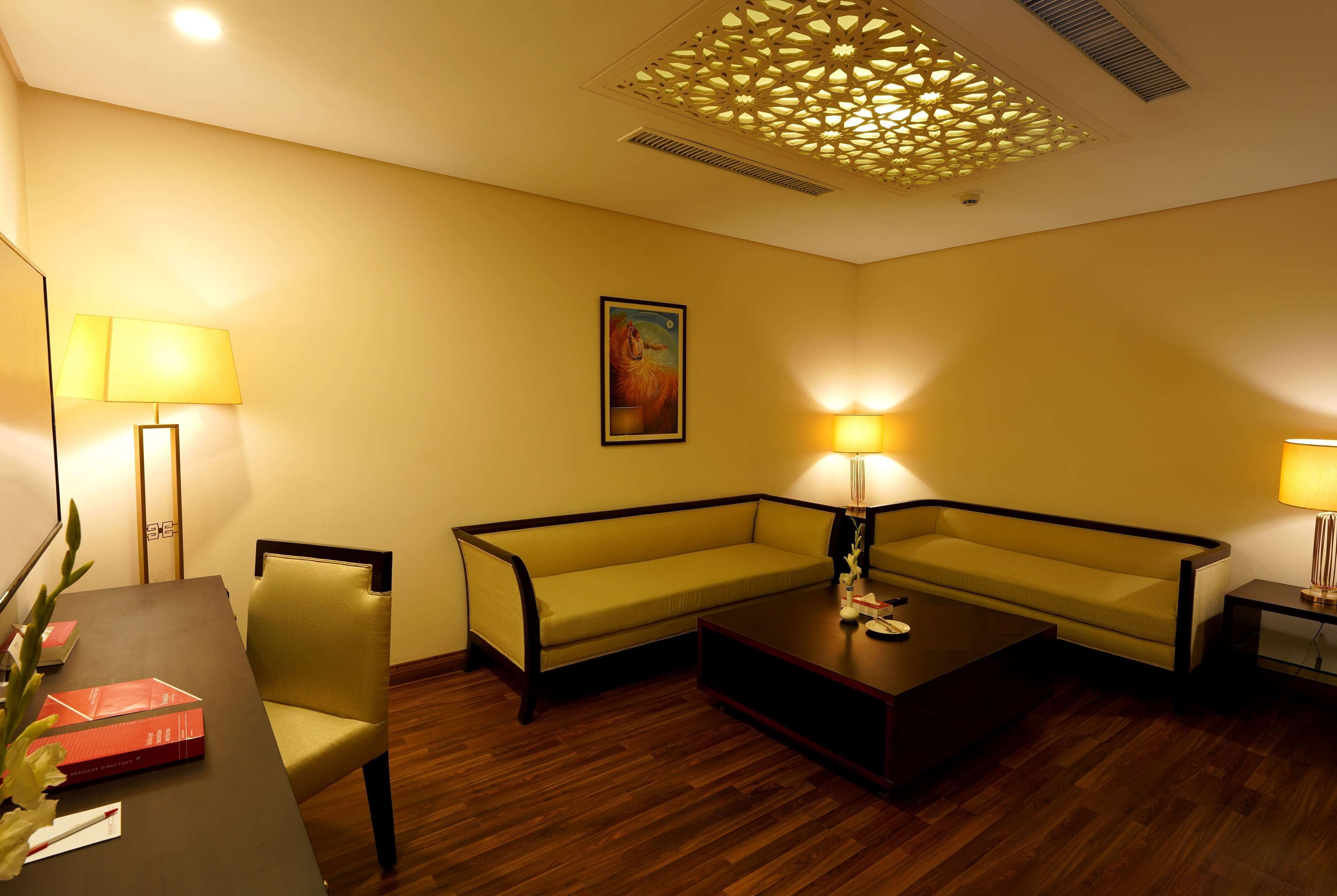 A room with a sofa, a coffee table, a lamp, and a painting on the wall.