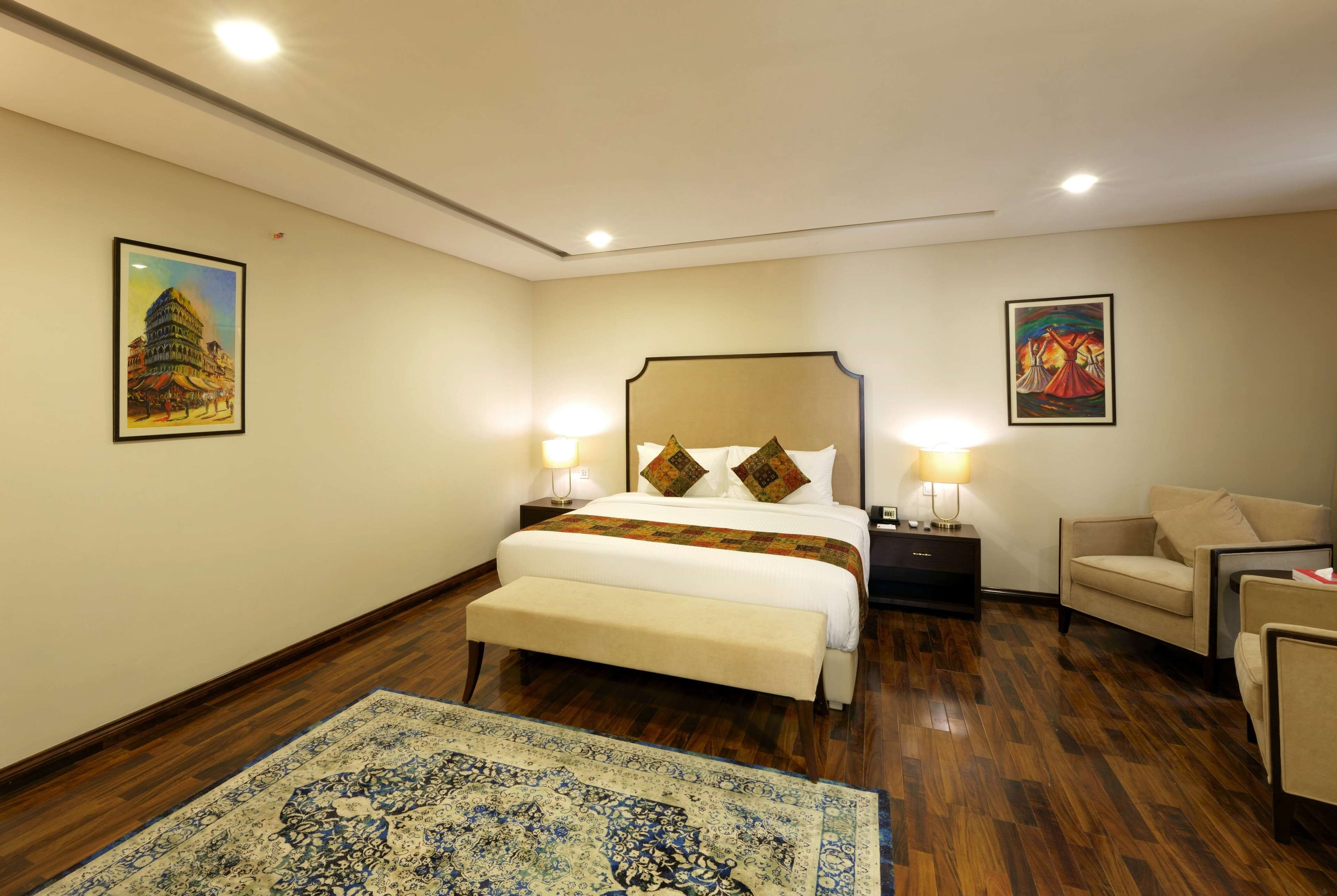 Una habitación de hotel con una cama grande, un banco, un escritorio y una silla.
