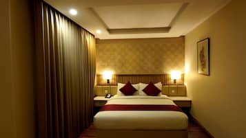 A hotel room with a large bed, two bedside tables with lamps, a patterned wall, and a curtain on the left.