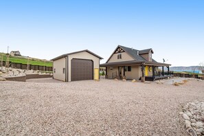 A two-story house with a garage, a covered porch, and a gravel driveway.