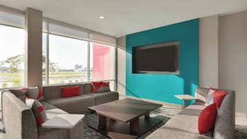 Una sala de estar moderna con un conjunto de sofás, una mesa de centro y un televisor de pantalla plana montado en una pared azul aguamarina.
