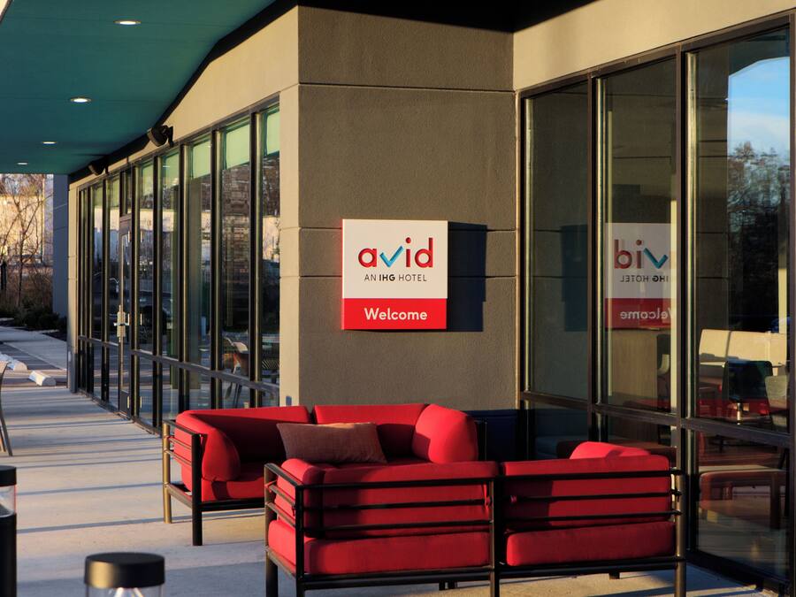 An Avid hotel exterior with a red sofa and a 'Welcome' sign.