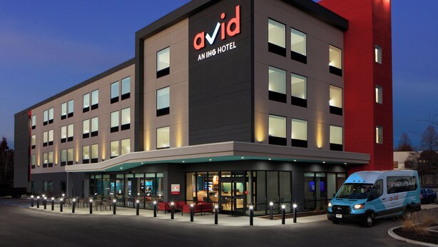 A modern hotel with a prominent 'Avid' sign, large windows, and a well-lit entrance.