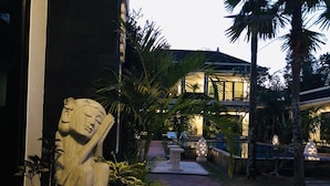A stone statue in a garden area with a pathway leading to a building. - Benian Villas (Nusa Dua)