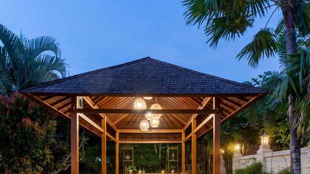 A covered outdoor seating area with wooden furniture and decorative lighting. - Benian Villas (Nusa Dua)