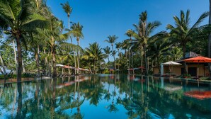 A clear pool surrounded by palm trees and umbrellas, with a building in the background. - Blue Chill private Pool Villa - Koh Chang (Ko Chang)
