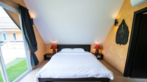 Ett sovrum med en säng, två sänglampor, en vägglampa och utsikt genom ett stort fönster.
