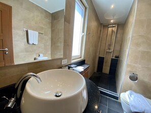Un baño moderno con un lavabo grande de color blanco, un espejo y una zona de ducha.