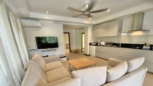 A modern living room with a beige sofa, a wooden coffee table, and a flat-screen TV.