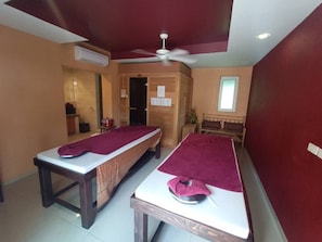 A room with two massage tables, a ceiling fan, and a window.