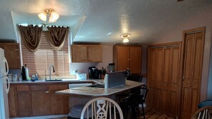 A compact kitchen with wooden cabinets, a dining table, and a built-in island.