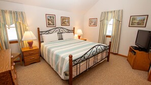 A neatly arranged bedroom with a bed, bedside lamps, a television, and framed pictures on the walls.