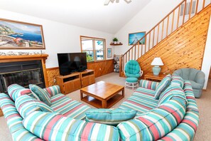A living room with a sofa, television, fireplace, and a staircase.