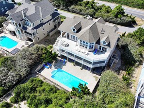 A large two-story house with a swimming pool, multiple decks, and a well-maintained garden. - OCEANFRONT, Private Pool, Rec Rm, Ocean Views! PI265, Mroning Star (Corolla)