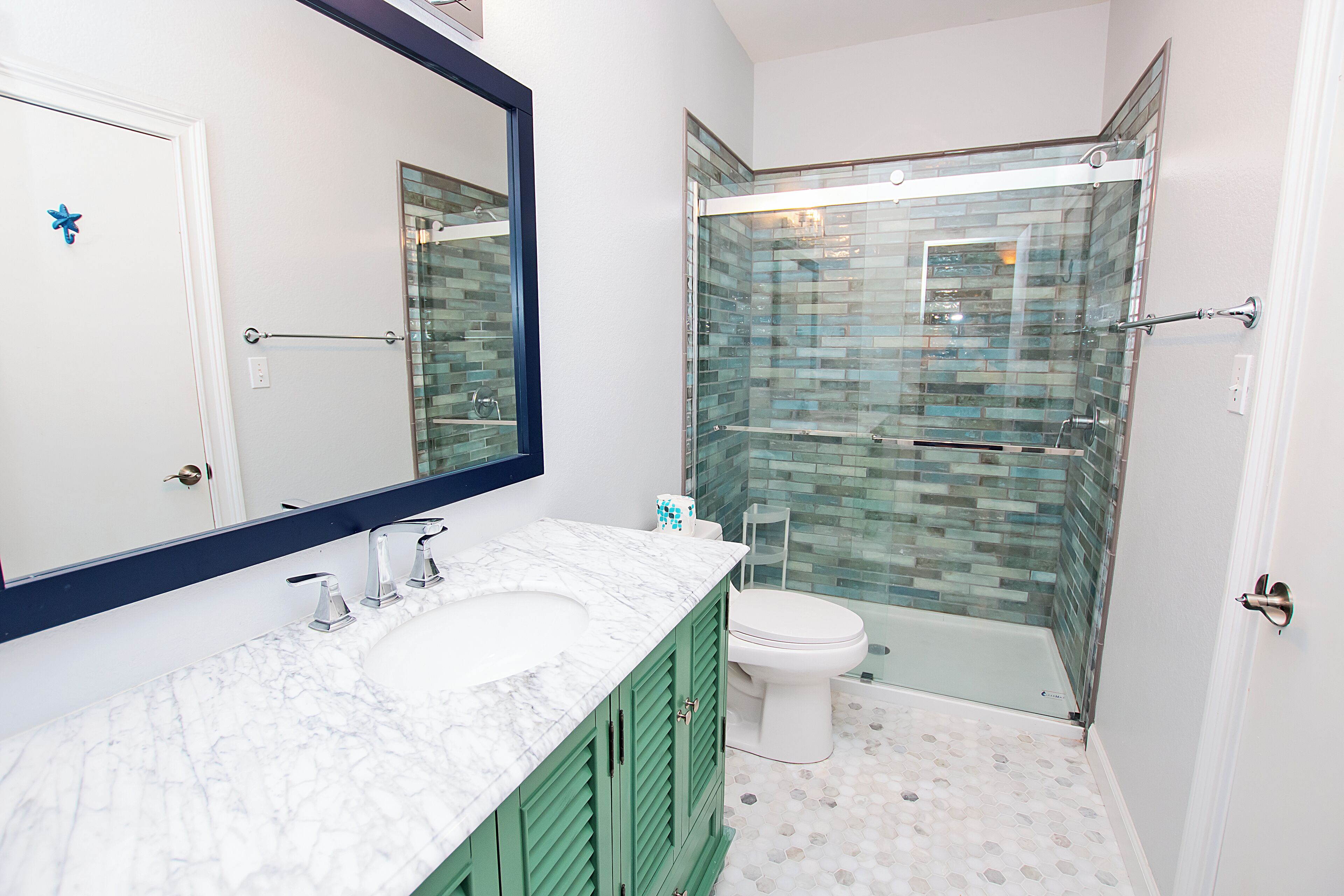 A bathroom with a glass-enclosed shower, a white toilet, and a marble sink.